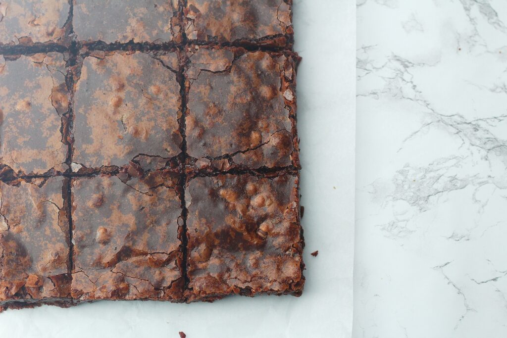 Top view of fudgy brownies on the parchment paper on top of a marble surface
