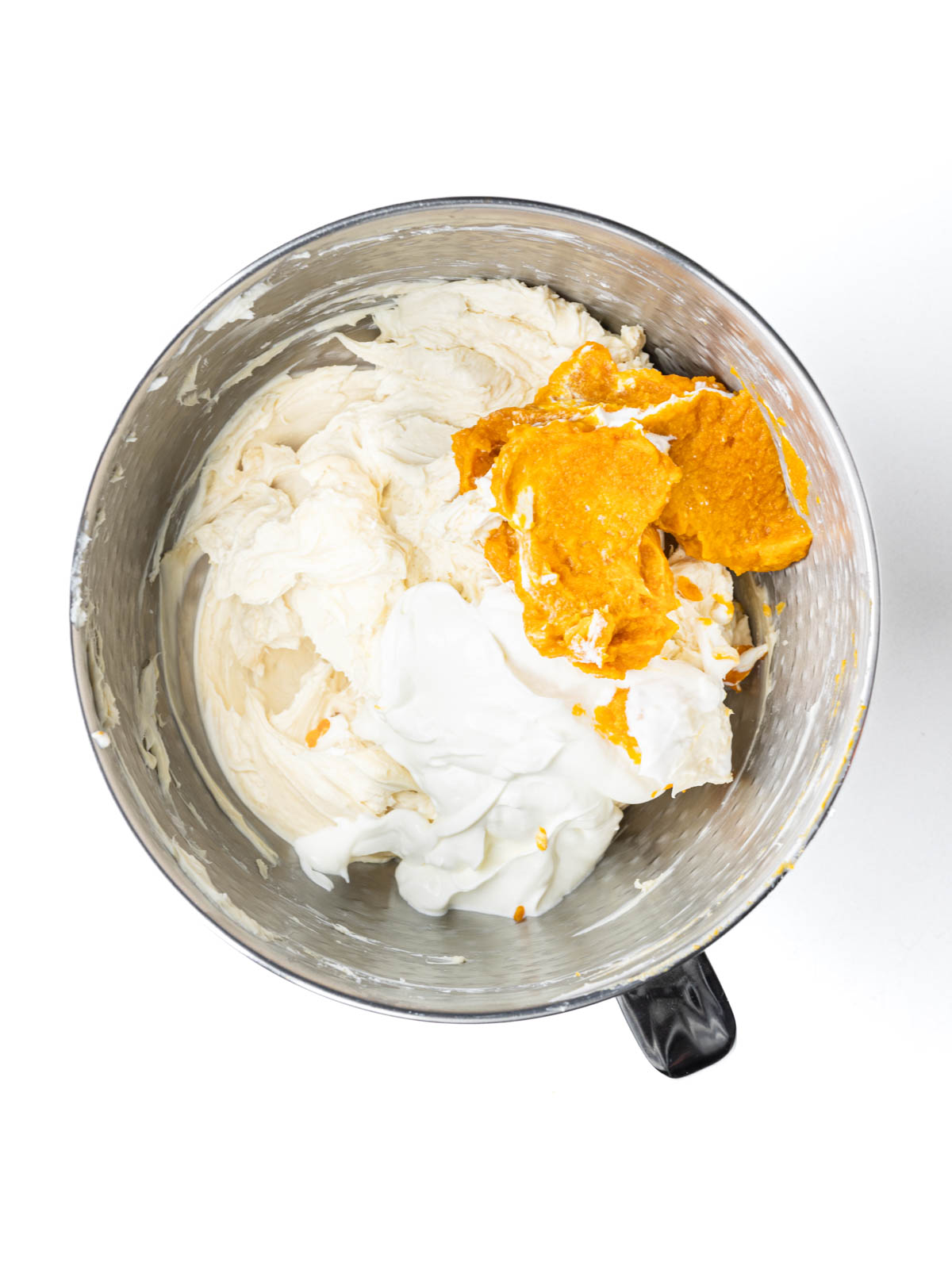 Pumpkin and sour cream added to the cream cheese mixture in a mixing bowl.