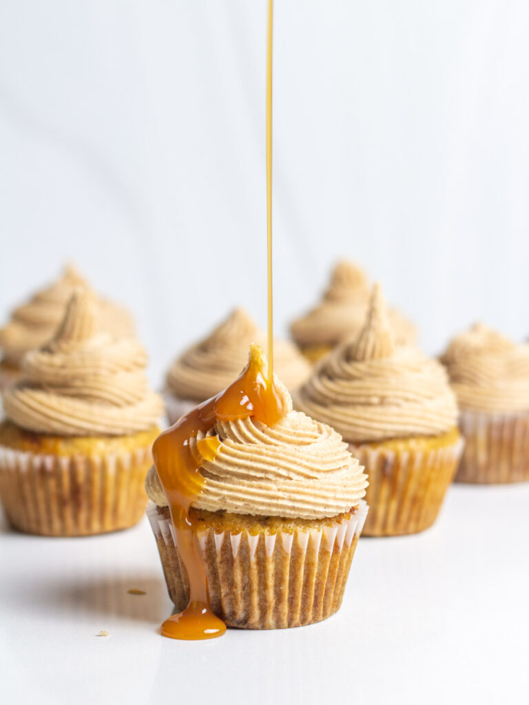 Caramel drizzling down onto frosted apple cider cupcakes.