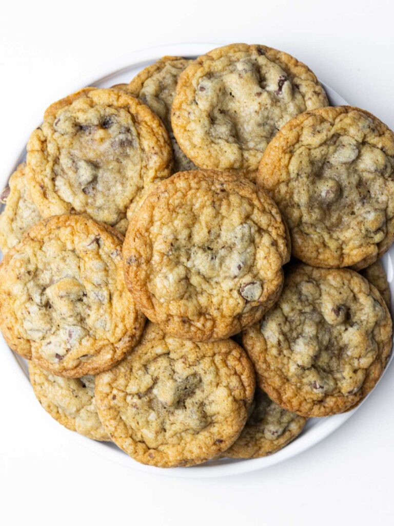A batch of chocolate chip cookies piled on a round plate.