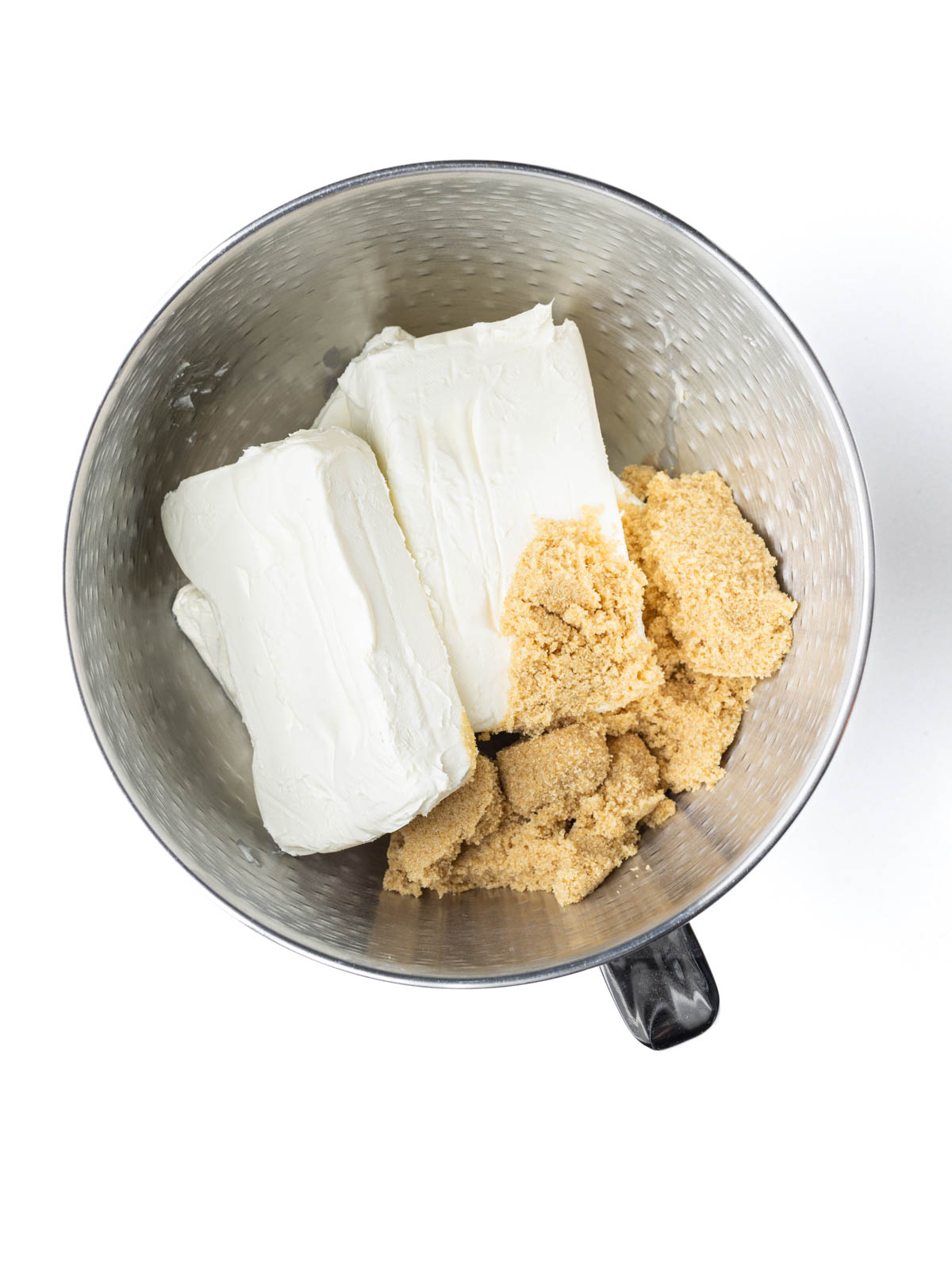 Four blocks of cream cheese in a mixing bowl with brown sugar.