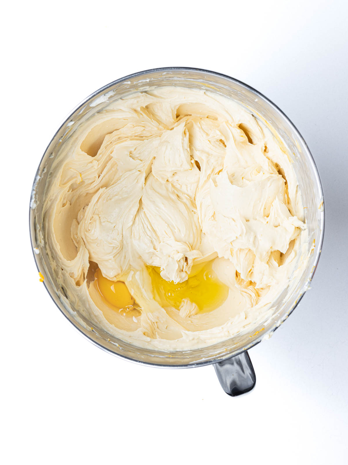 Eggs added to the pumpkin cheesecake filling in the mixing bowl.