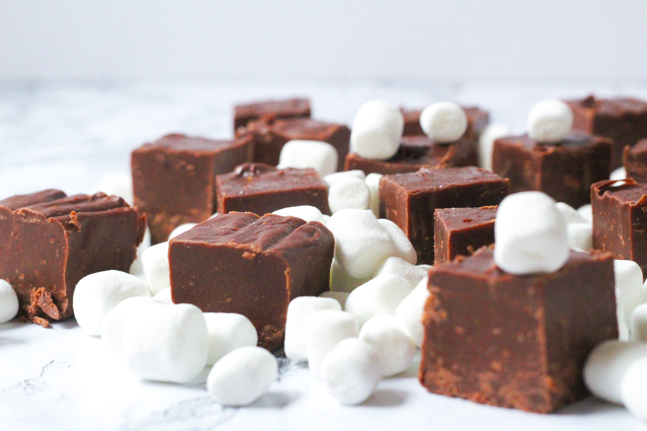 Side few of cubes of brown hot cocoa fudge surrounded by mini marshmallows