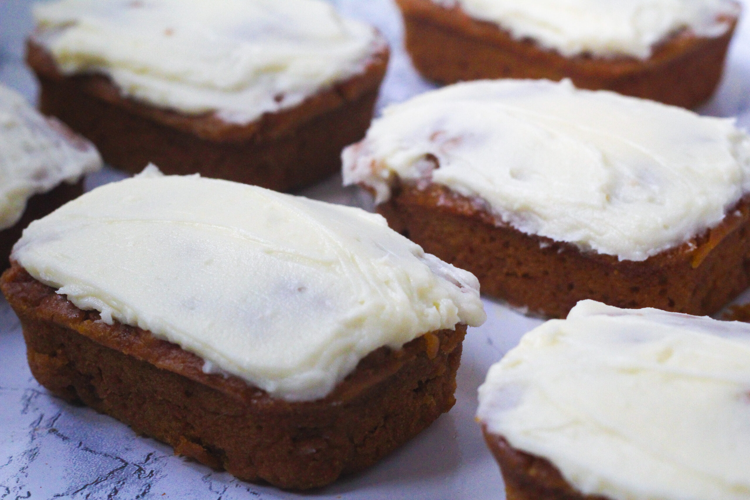 angled view of pumpkin chai breads topped with a thin layer of cream cheese frosting.