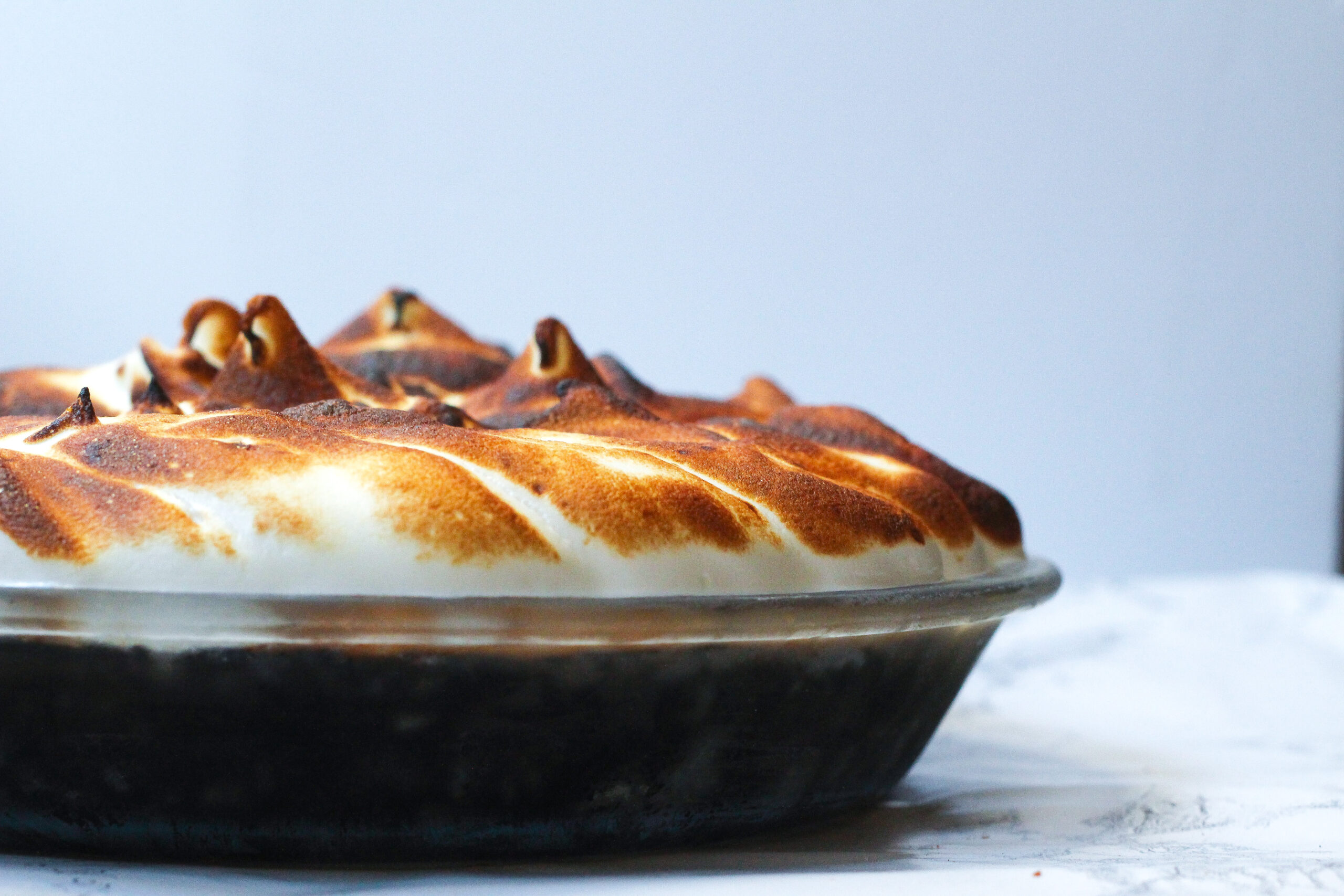 Side view of a mocha meringue pie, cutting out of frame on the left side of the image
