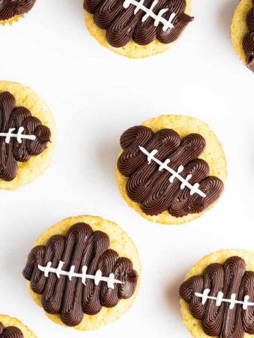 A top down view of a batch of football cupcakes on a white background.