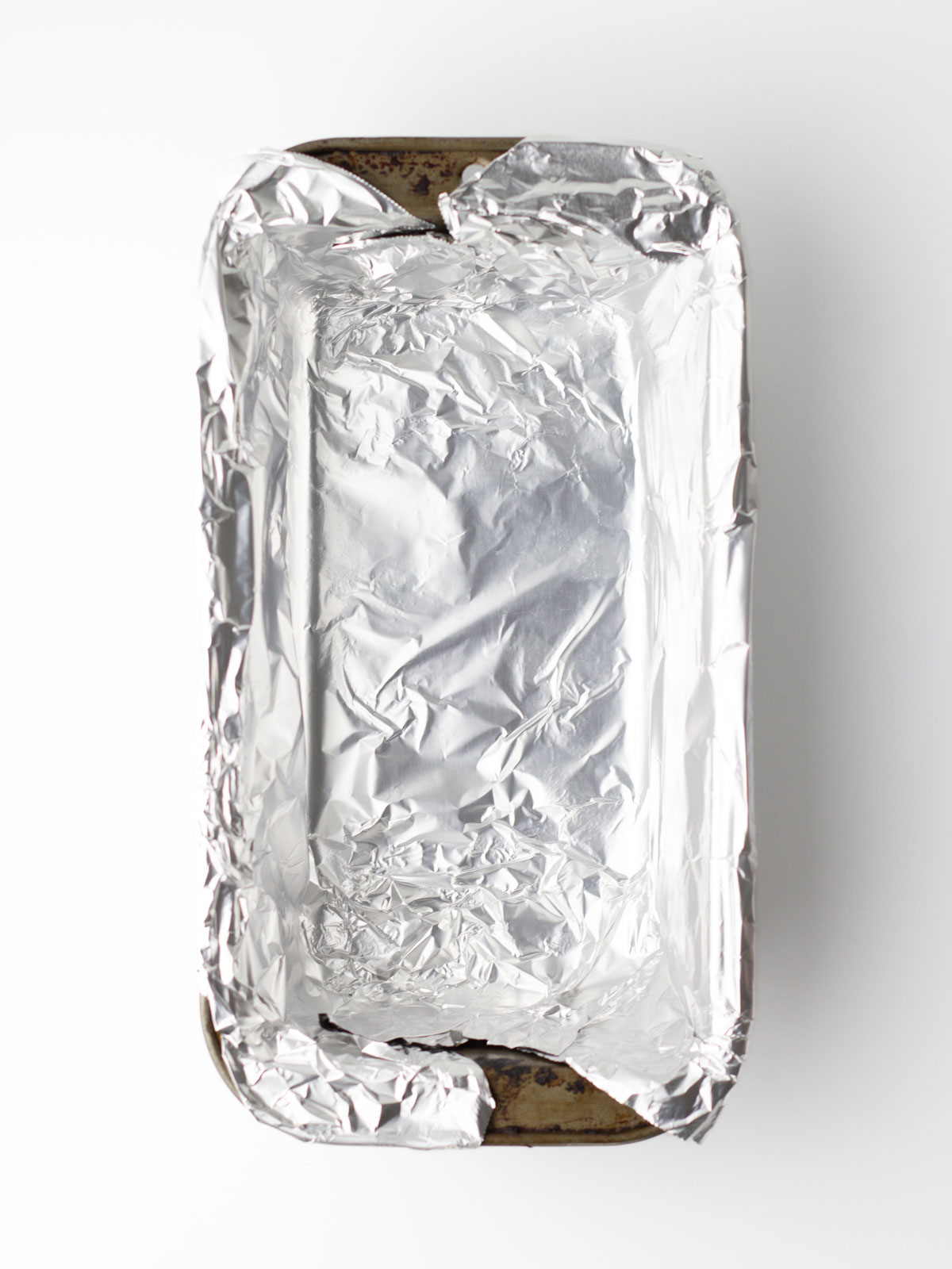 A metal loaf pan lined with aluminum foil.