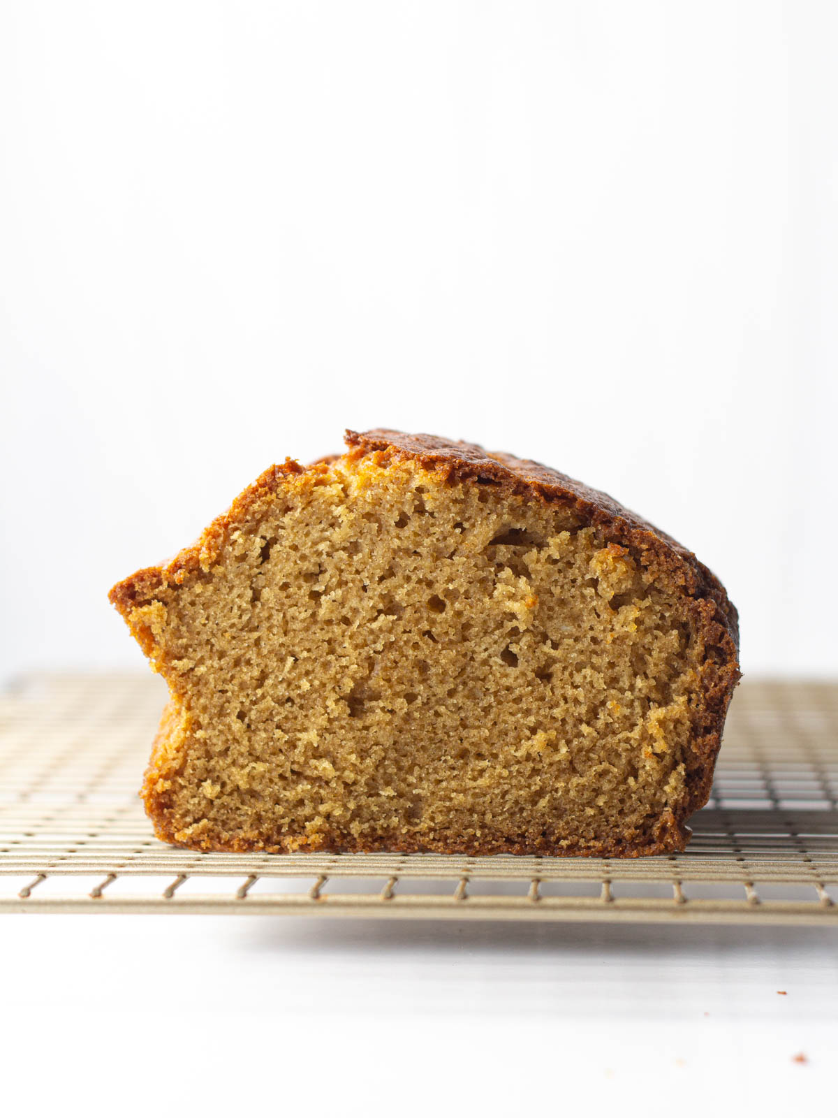 Side view of the cut side of a loaf of chai bread on top of a gold wire rack.