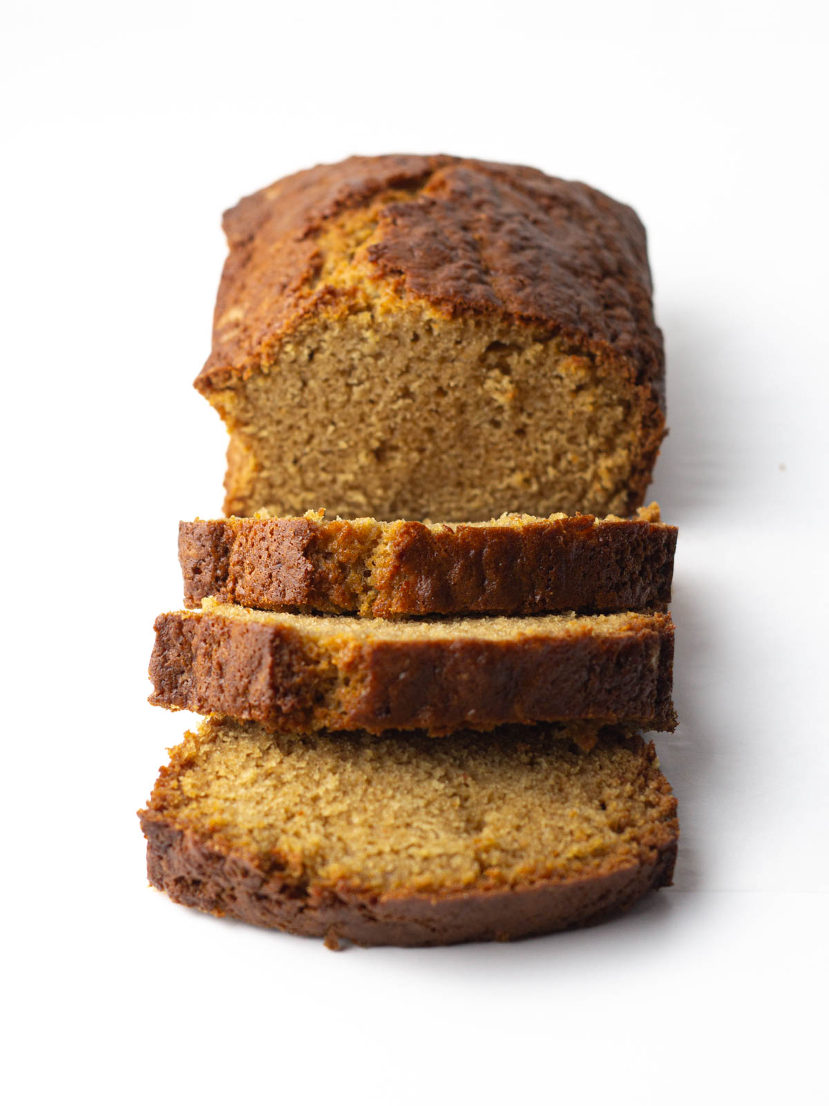 An angled view of a loaf of chai bread with three slices cut and leaning away from the rest of the loaf.