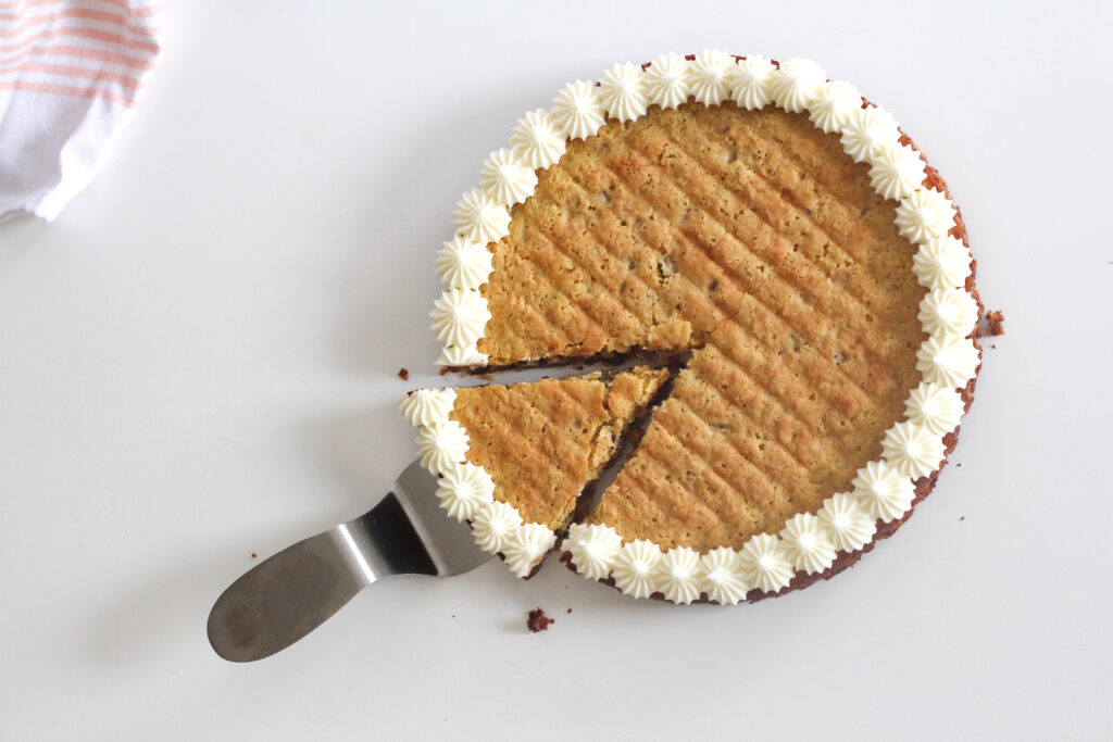 Slice of gluten free chocolate chip cookie cake on cake server slightly removed from the cake.