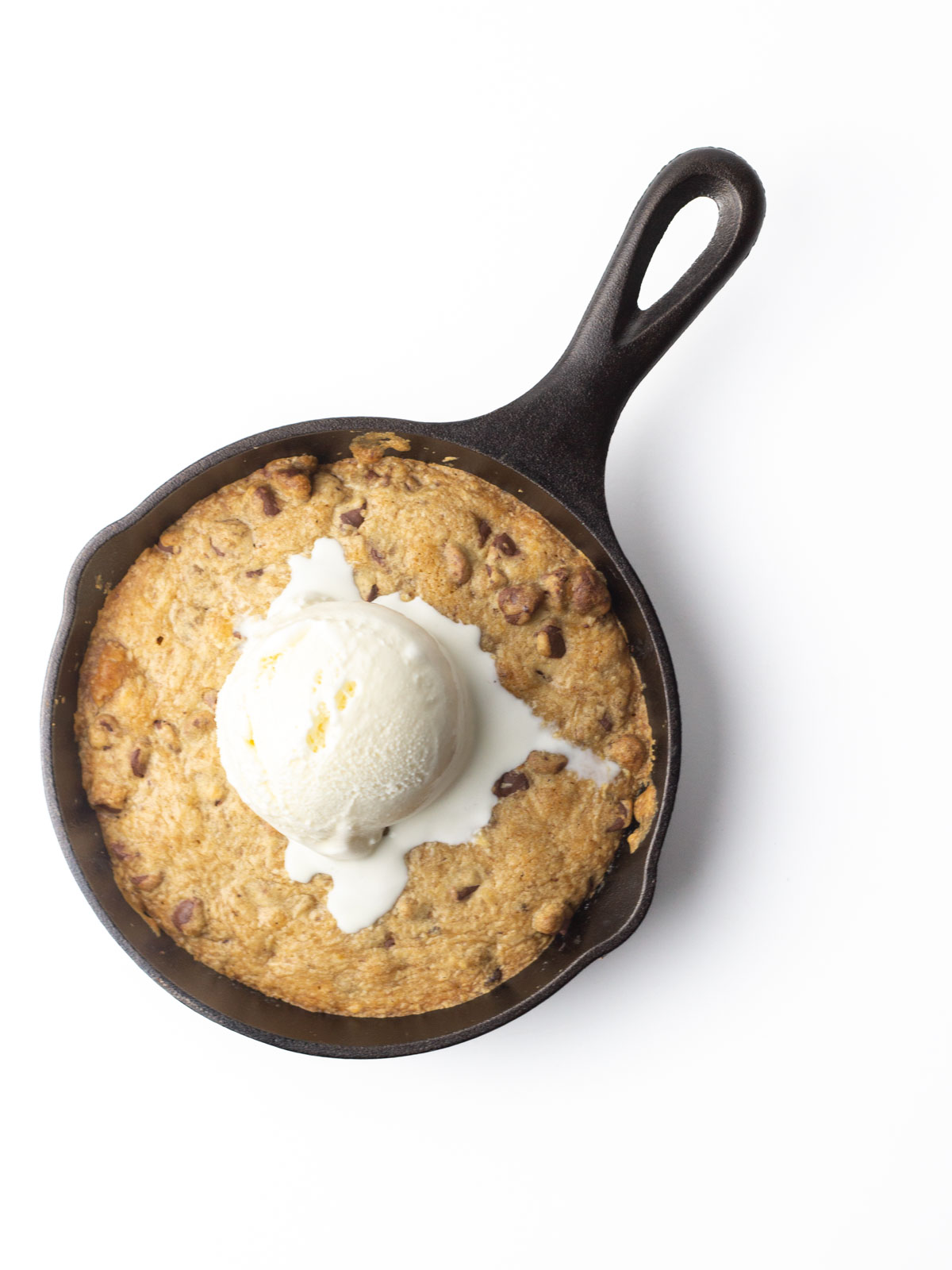 Chocolate chip cookie baked into a 6.5" cast iron skillet with a melting scoop of vanilla ice cream on top.