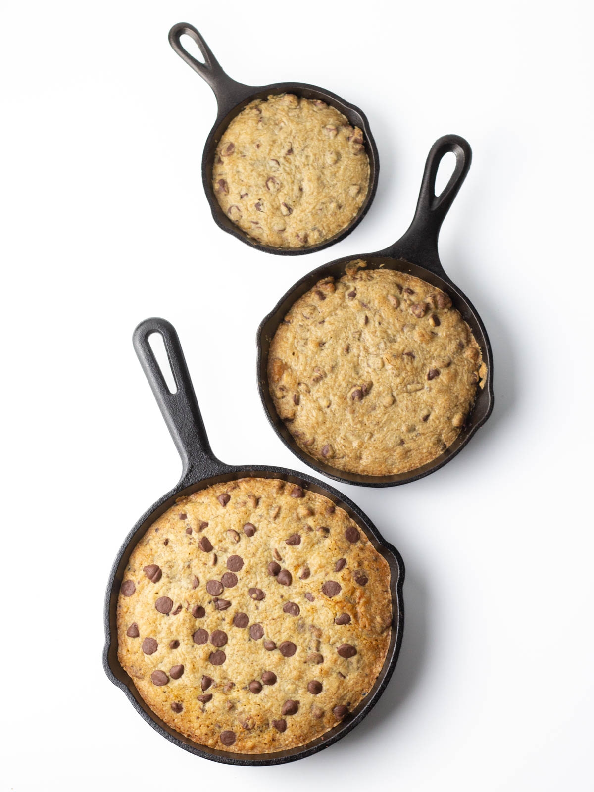 A 5" cast iron skillet cookie at the top, a 6.5" cast iron skillet cookie in the middle, and an 8" cast iron skillet cookie at the bottom.