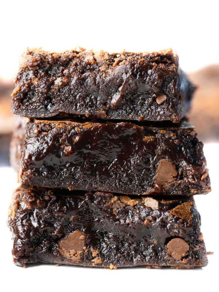 A close up of the stack of three brownies showing the fudgy centers and studded with chocolate chips.