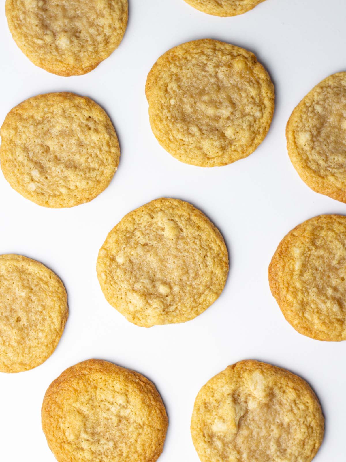 Baked beer cookies without icing spread around a white surface.