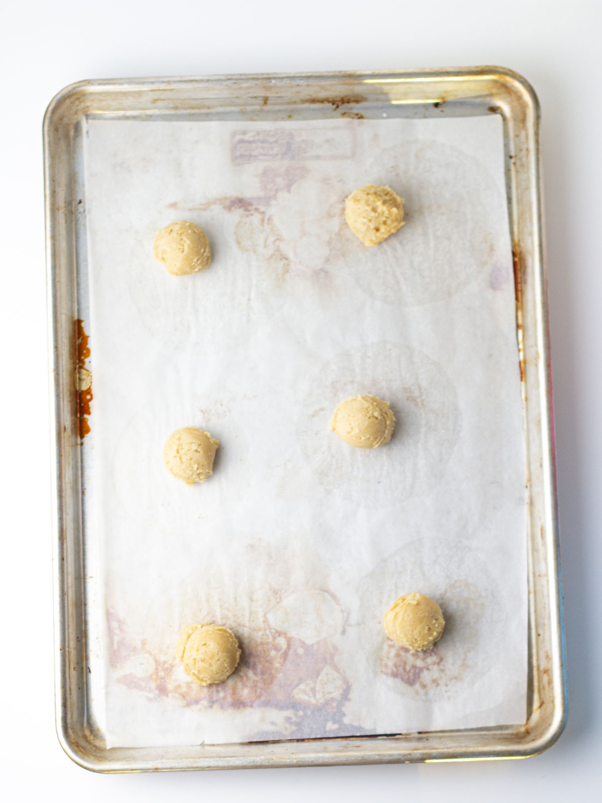 Balls of beer cookie dough on a parchment lined baking sheet.