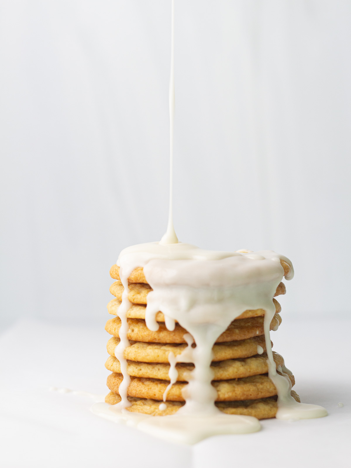 A stack of beer cookies with white icing glaze drizzling down on top and dripping down the front and sides of the stack.