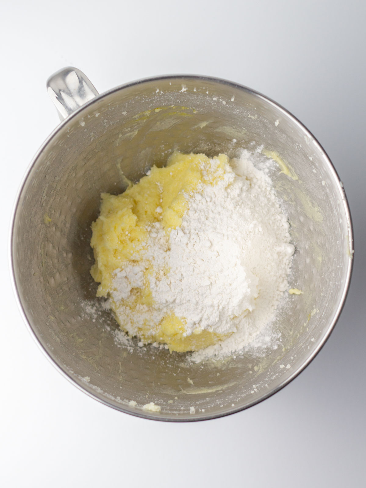 Flour mixture added to the batter in a silver mixing bowl.