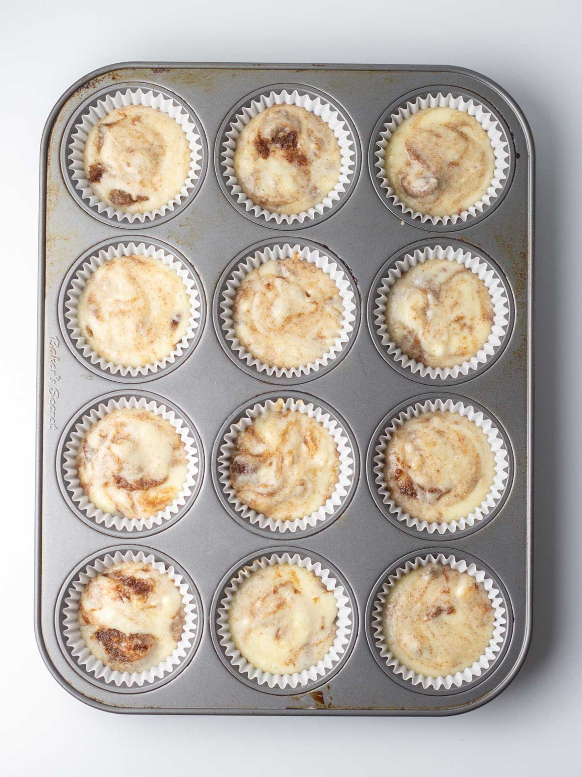 Cupcake batter in paper liners of muffin tin.