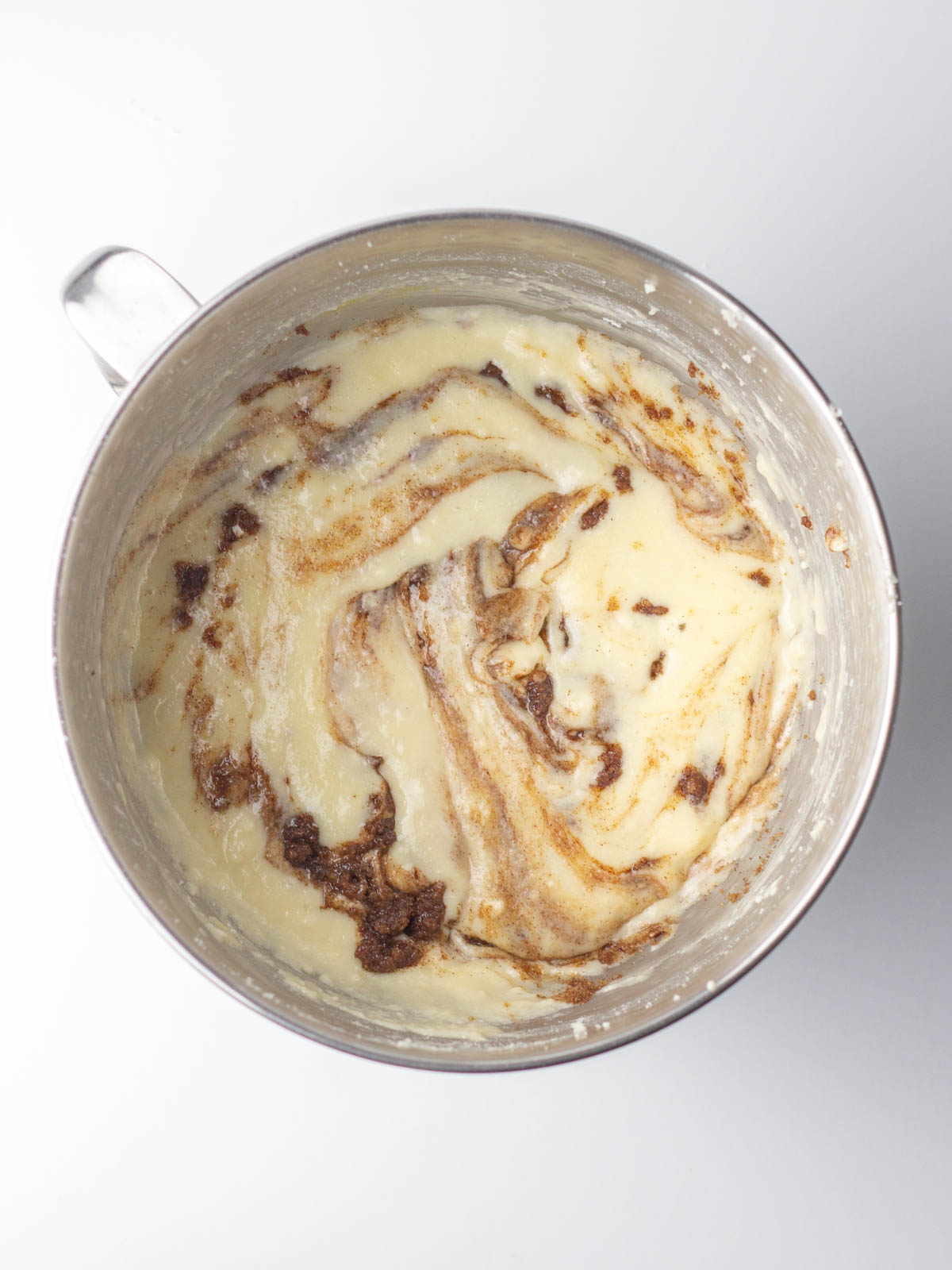 Cinnamon filling swirled into cupcake batter in a silver bowl.