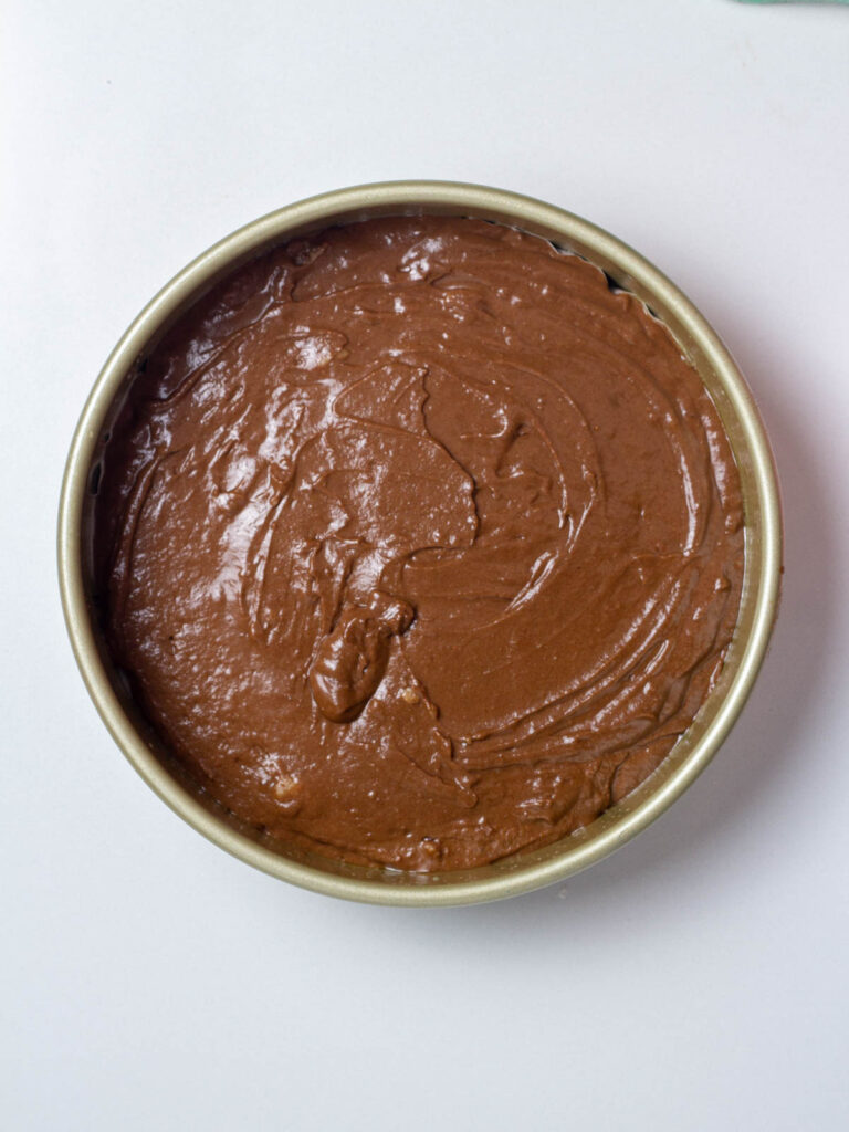 Spicy Chocolate Cake batter in a gold round cake pan.