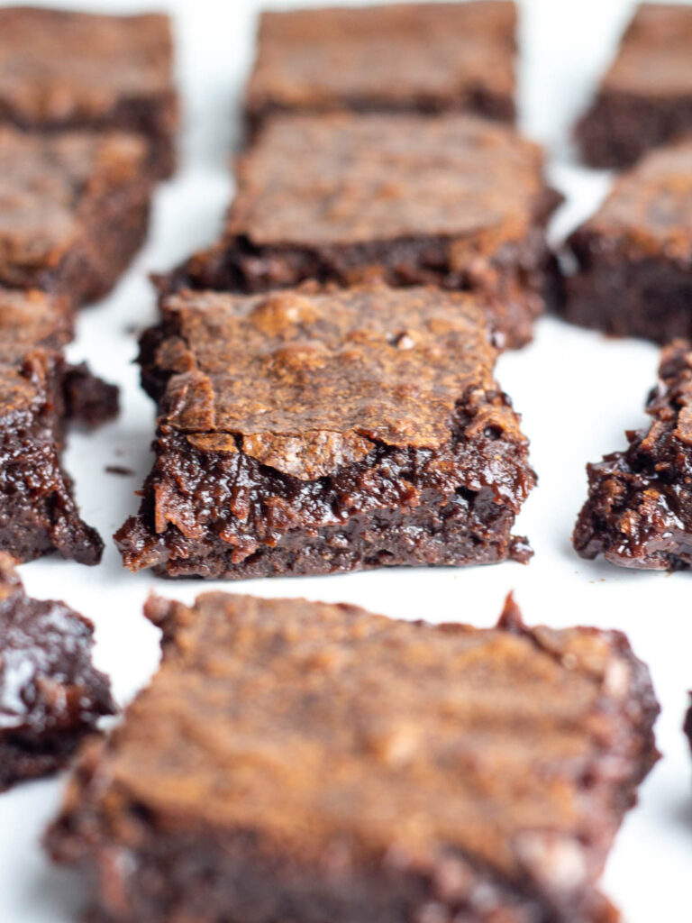Brownies cut into squares and spread out with the focus on the fudgy center of one central brownie.