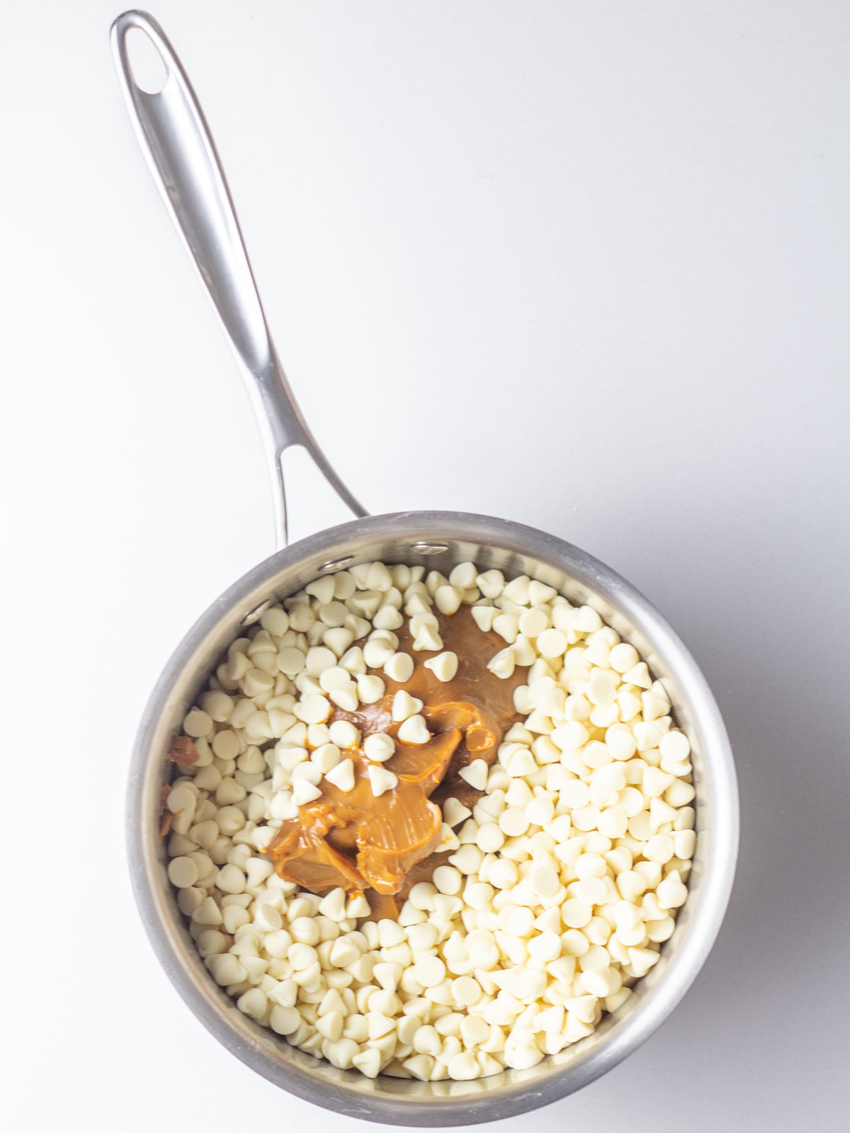 A saucepan filled with white chocolate chips and dulce de leche.