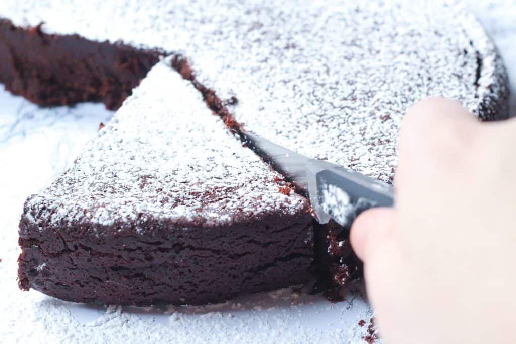 slicing a piece of kosher for passover red wine flourless chocolate cake.
