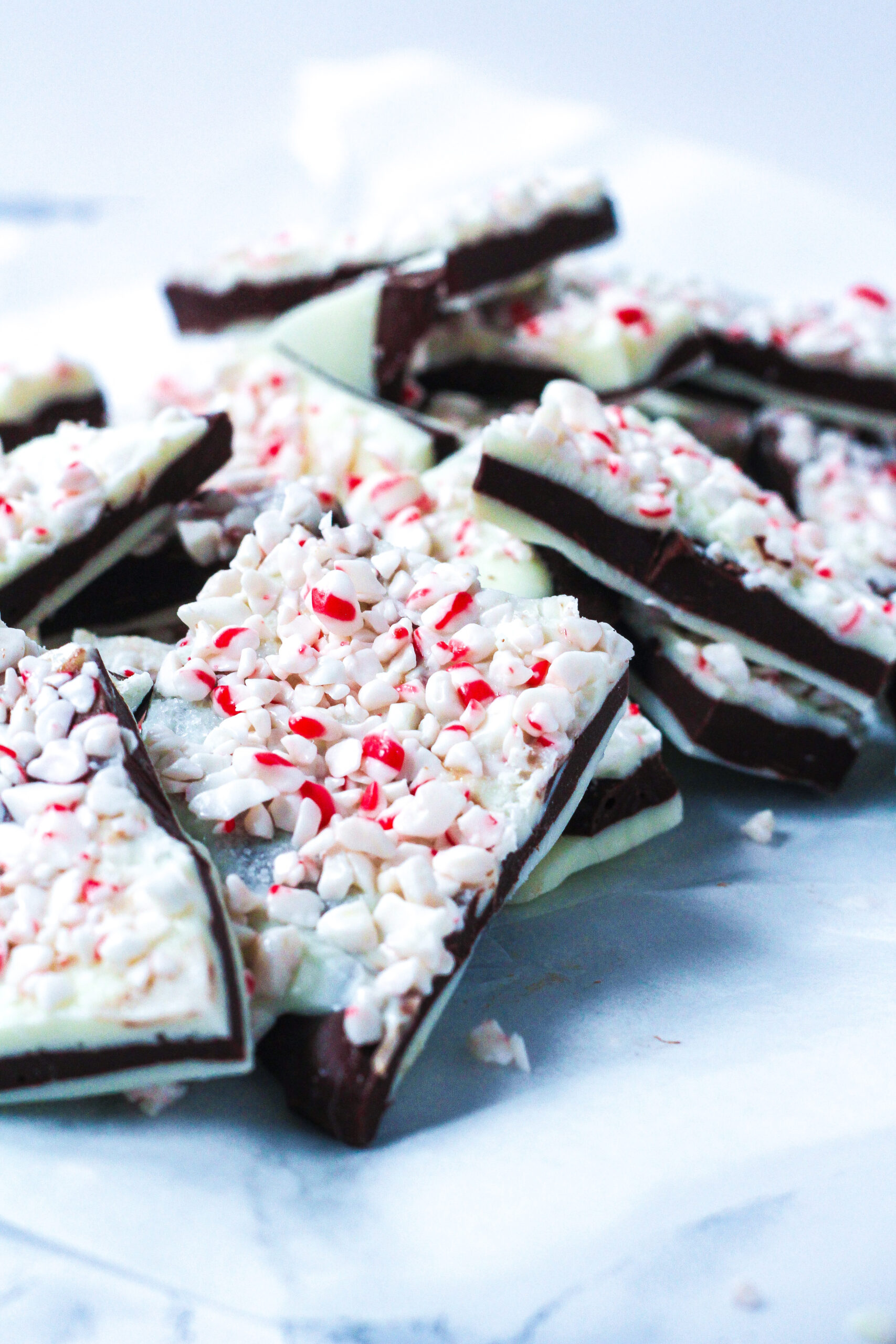 an angled close up of a pile of salted peppermint bark on a white marbled surface