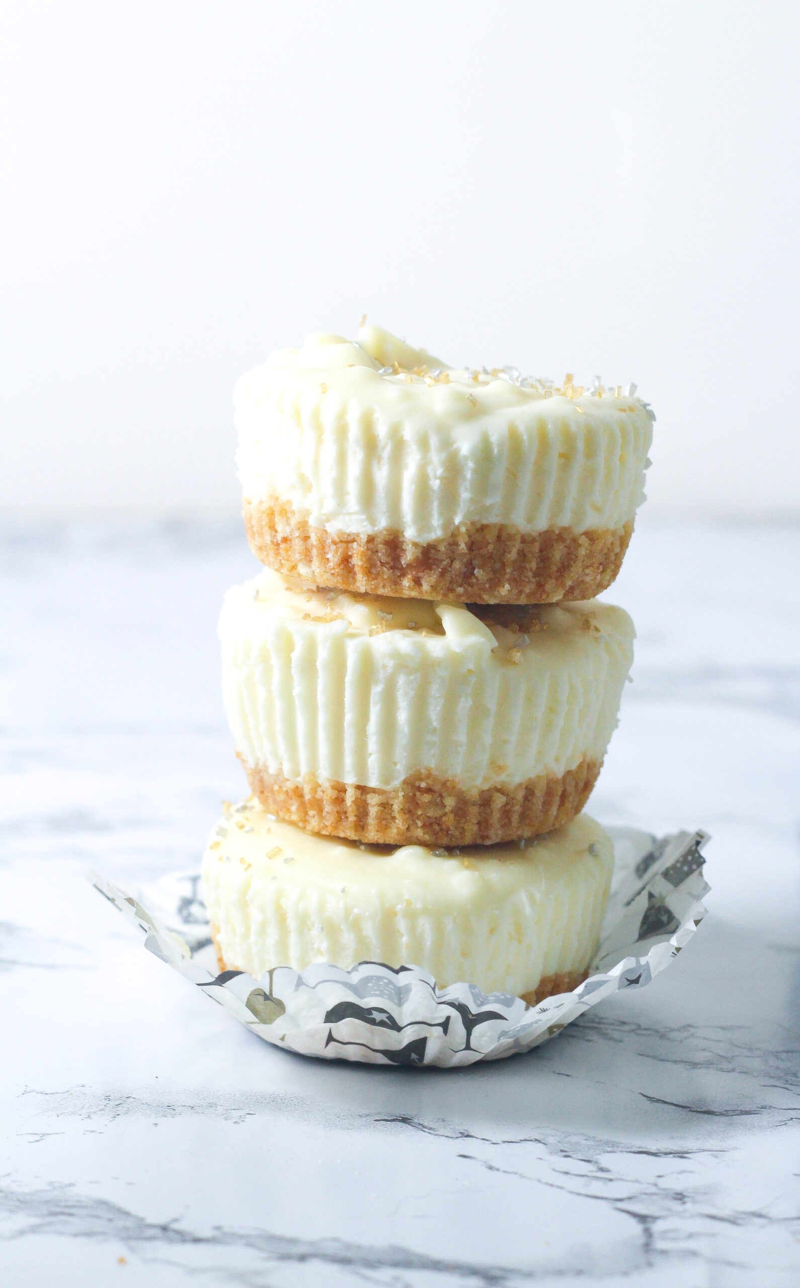 stack of three prosecco cheesecakes in an open cupcake wrapper on a marbled surface