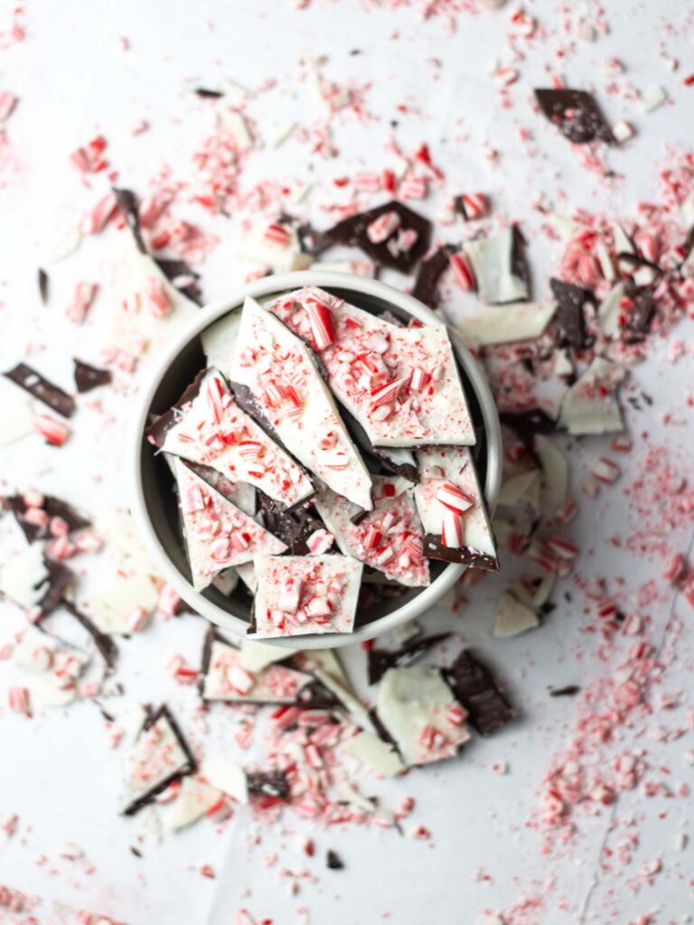 a bowl of salted peppermint bark surrounded by more peppermint bark and peppermint pieces.
