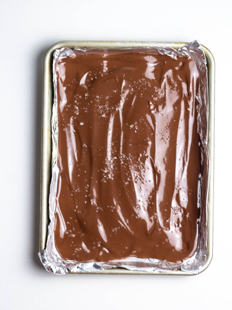 A quarter sheet pan filled with melted chocolate and topped with sea salt.