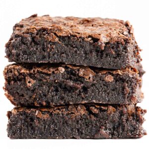 A close up of a stack of three fudgy stout beer brownies on a white background.