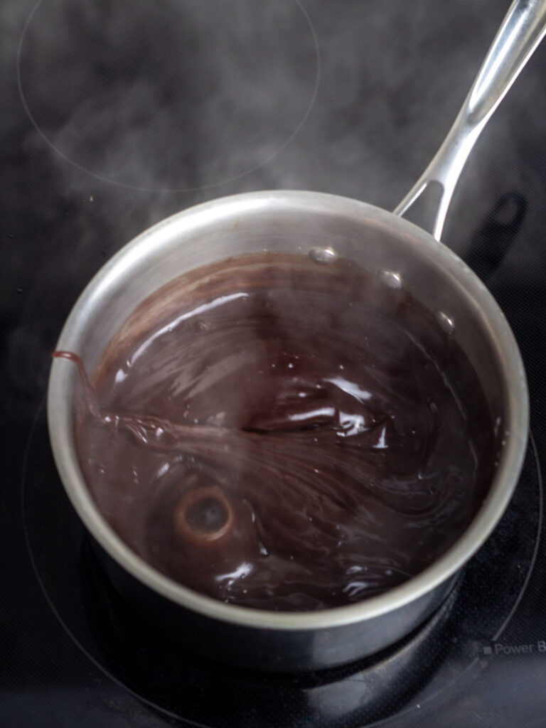 Hot chocolate pie filling boiling in a saucepan on the stove.
