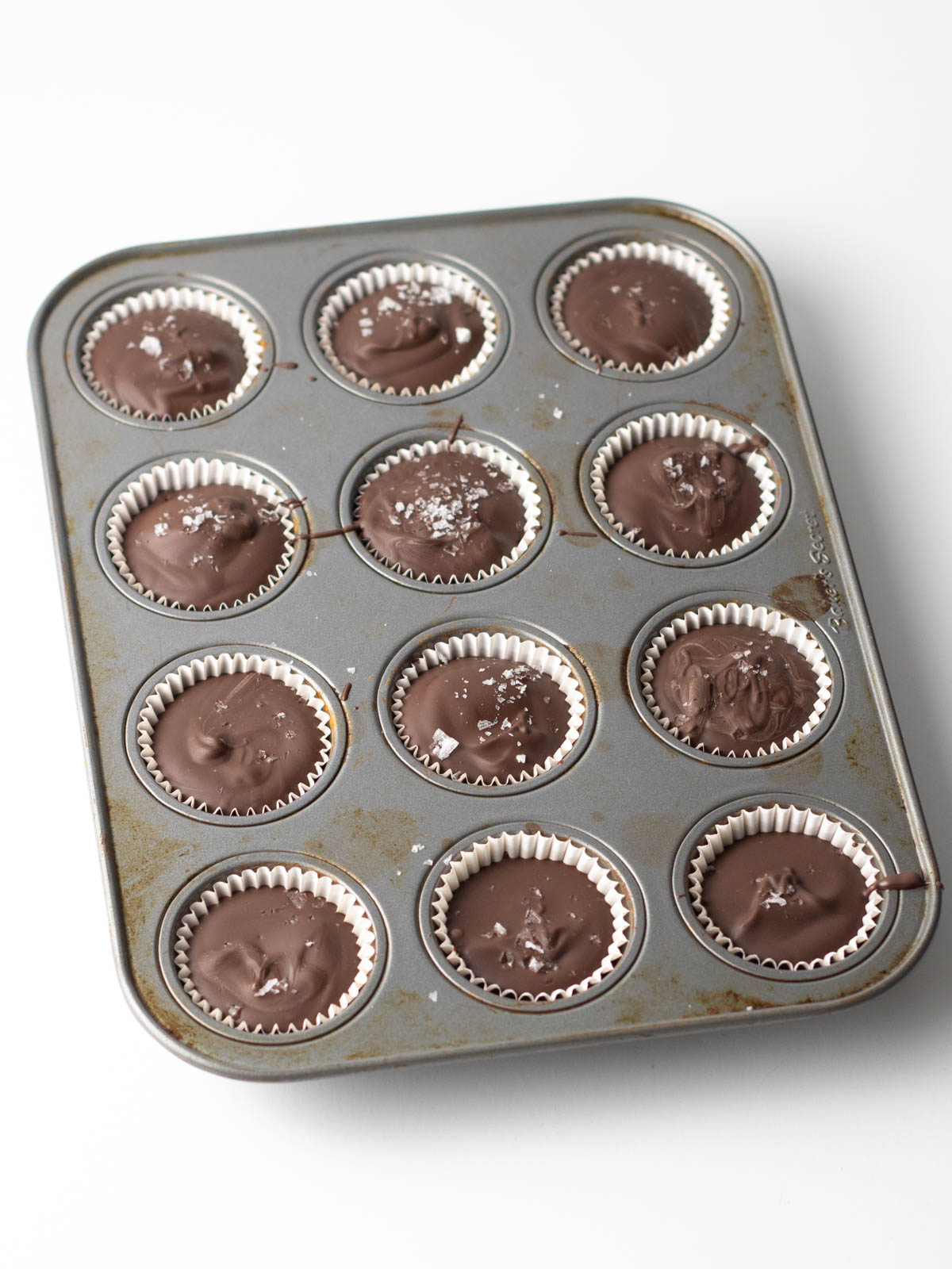 Nutella cups topped with sea salt in a 12 cup mini muffin tin.