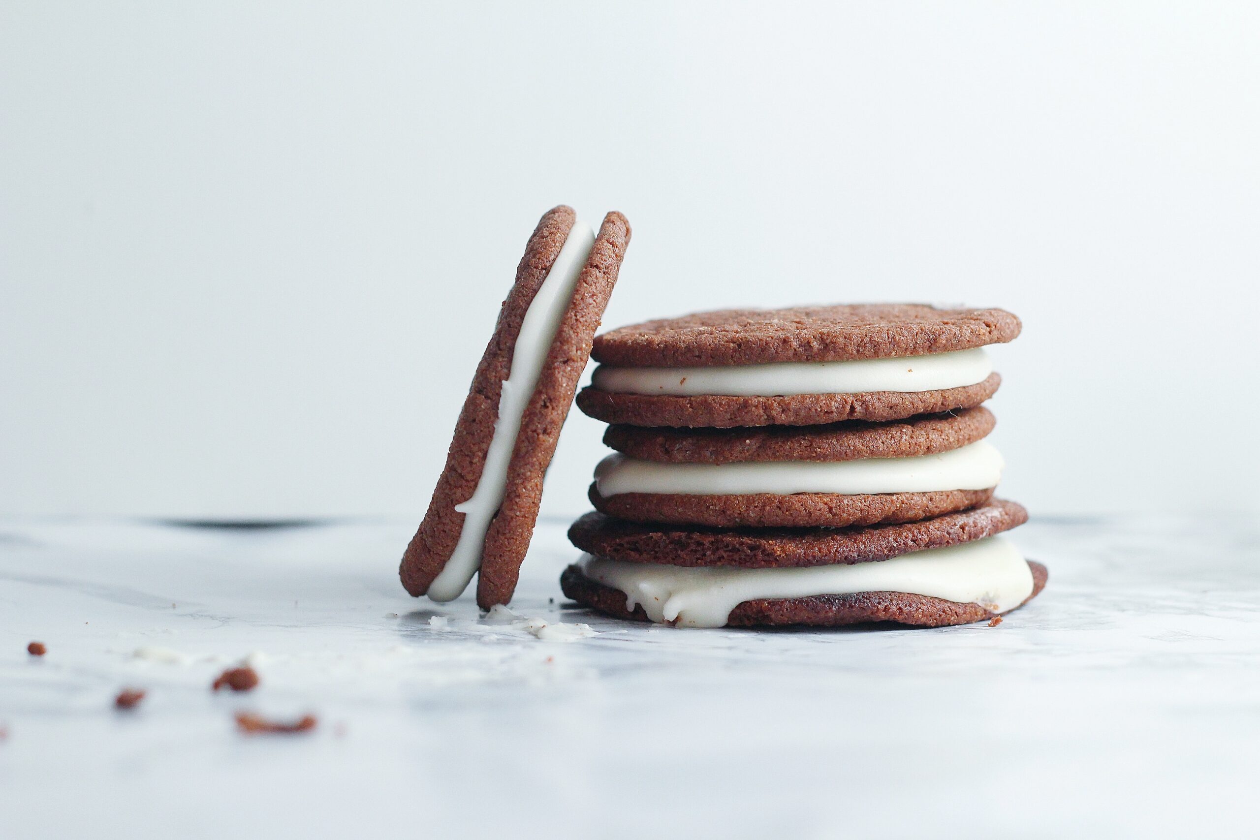 stack of three creme egg cookies with a fourth to the left of the stack leaning against the stack, with some crumbs in front left of the image