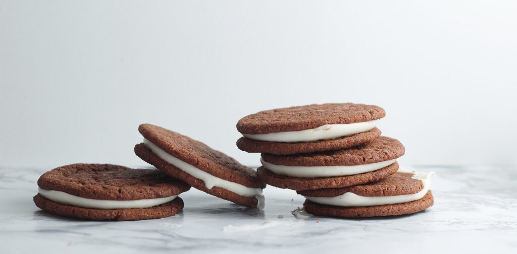 Stacks of chocolate cookie sandwiches with creme egg filling leaning on each other.