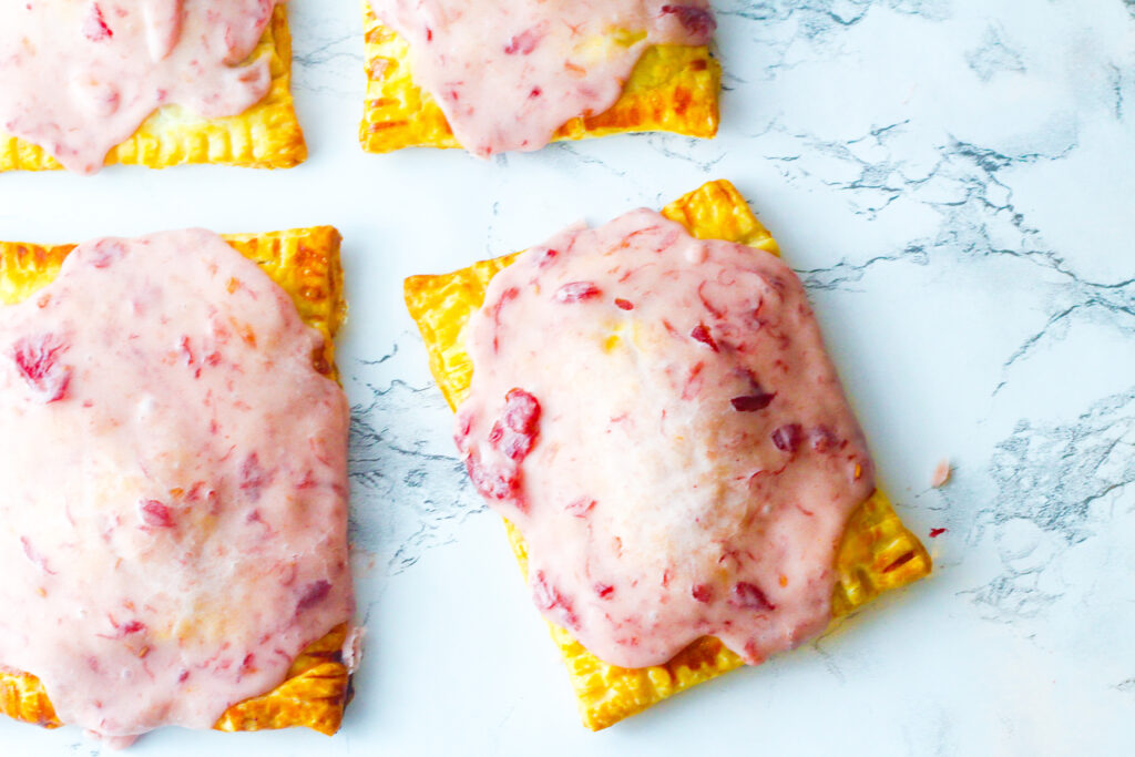 top down view of sangria poptarts on a marbled surface. There is one full poptart taking up a majority of the frame, sitting angled, with the edge of a poptart each to the left of it and above it, and the corner of a poptart to the upper left corner of it. It appears as though the poptarts going out of the frame are aligned in straight rows and the main poptart in the frame is slightly skewed.I