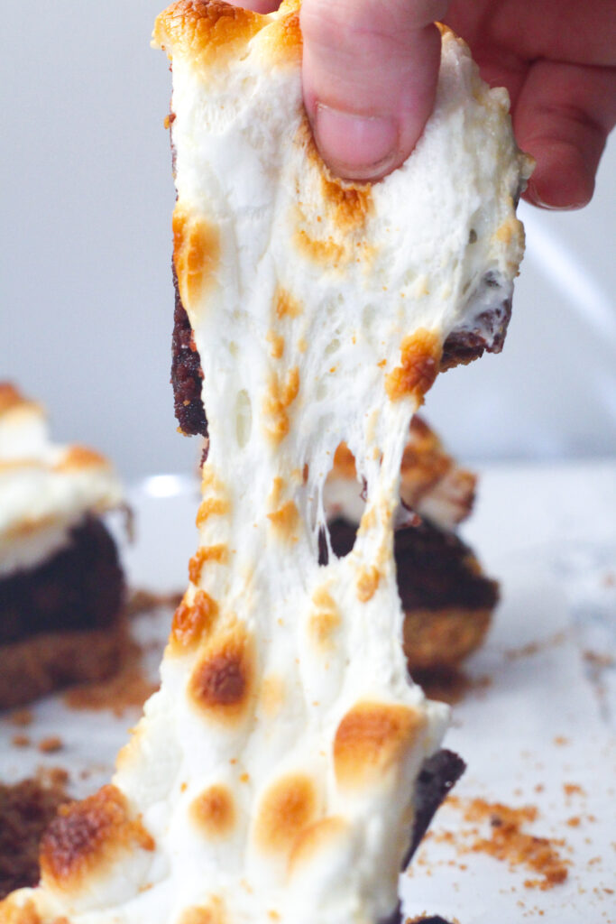 Close up of the marshmallow pull, stretching the toasted marshmallow topping between two Bailey's S'mores brownies