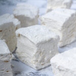 Angled view of maple marshmallows spread around a white marbled surface