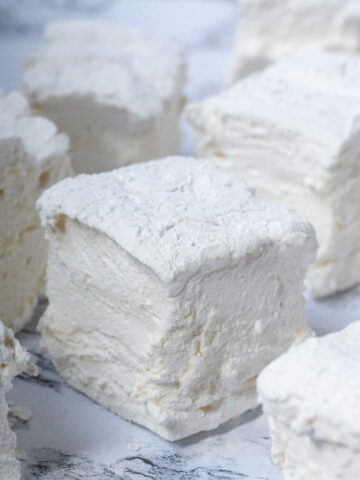 Angled view of maple marshmallows spread around a white marbled surface