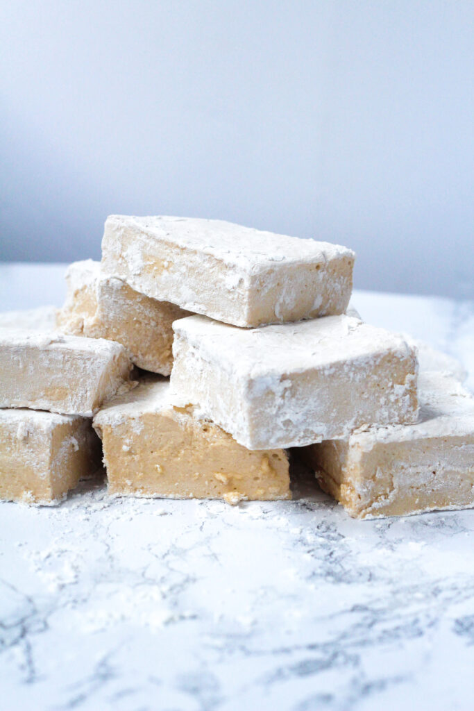 side view of a stack of chai marshmallows on a white marbled surface in front of a white background