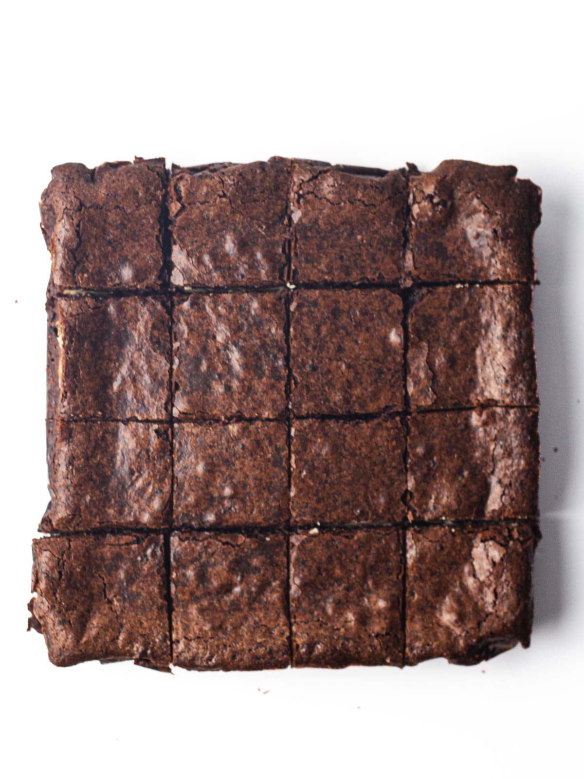 A batch of brownies cut into squares on a white surface.