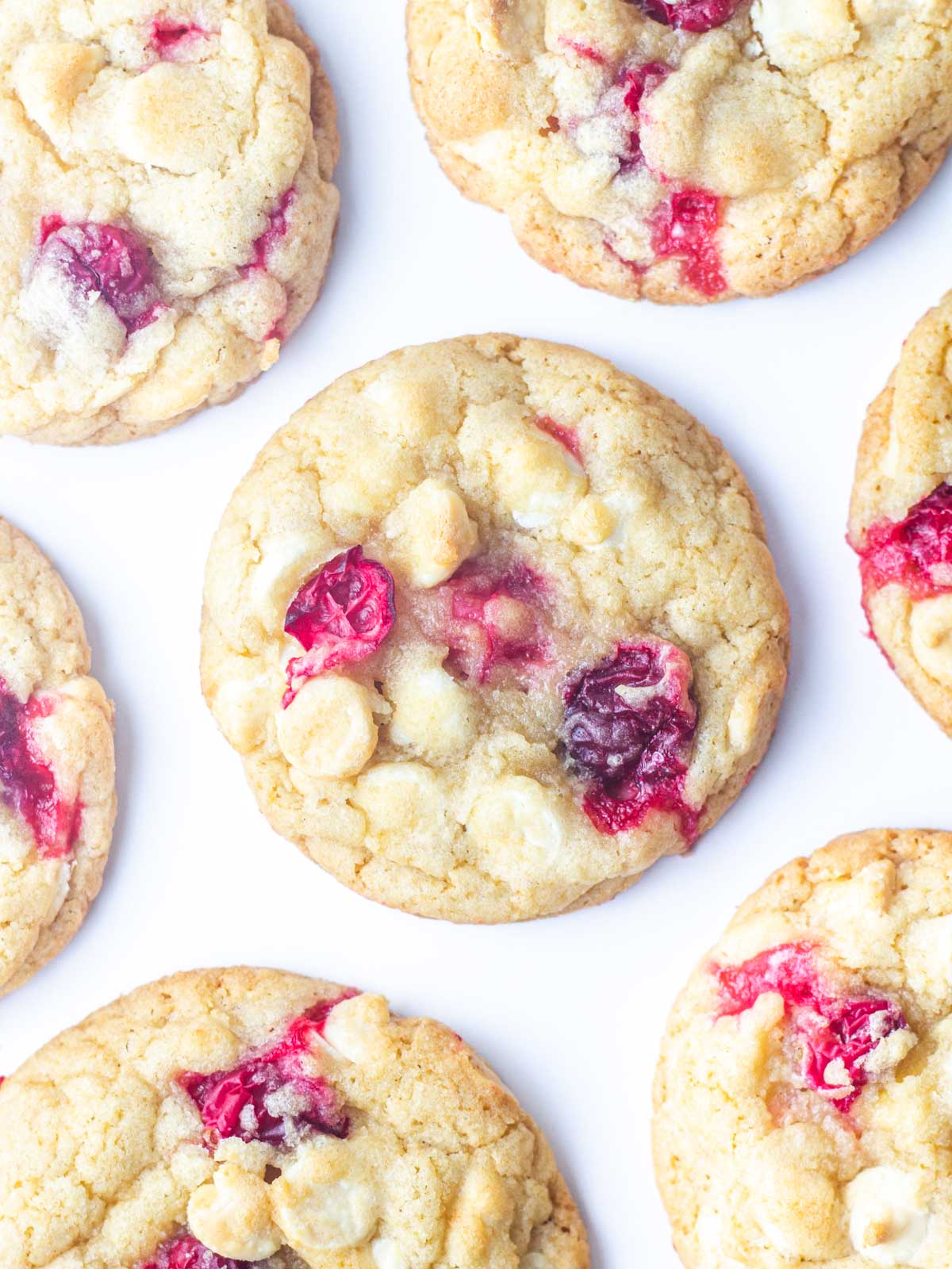 Top down view of cranberry white chocolate cookies on a white surface.