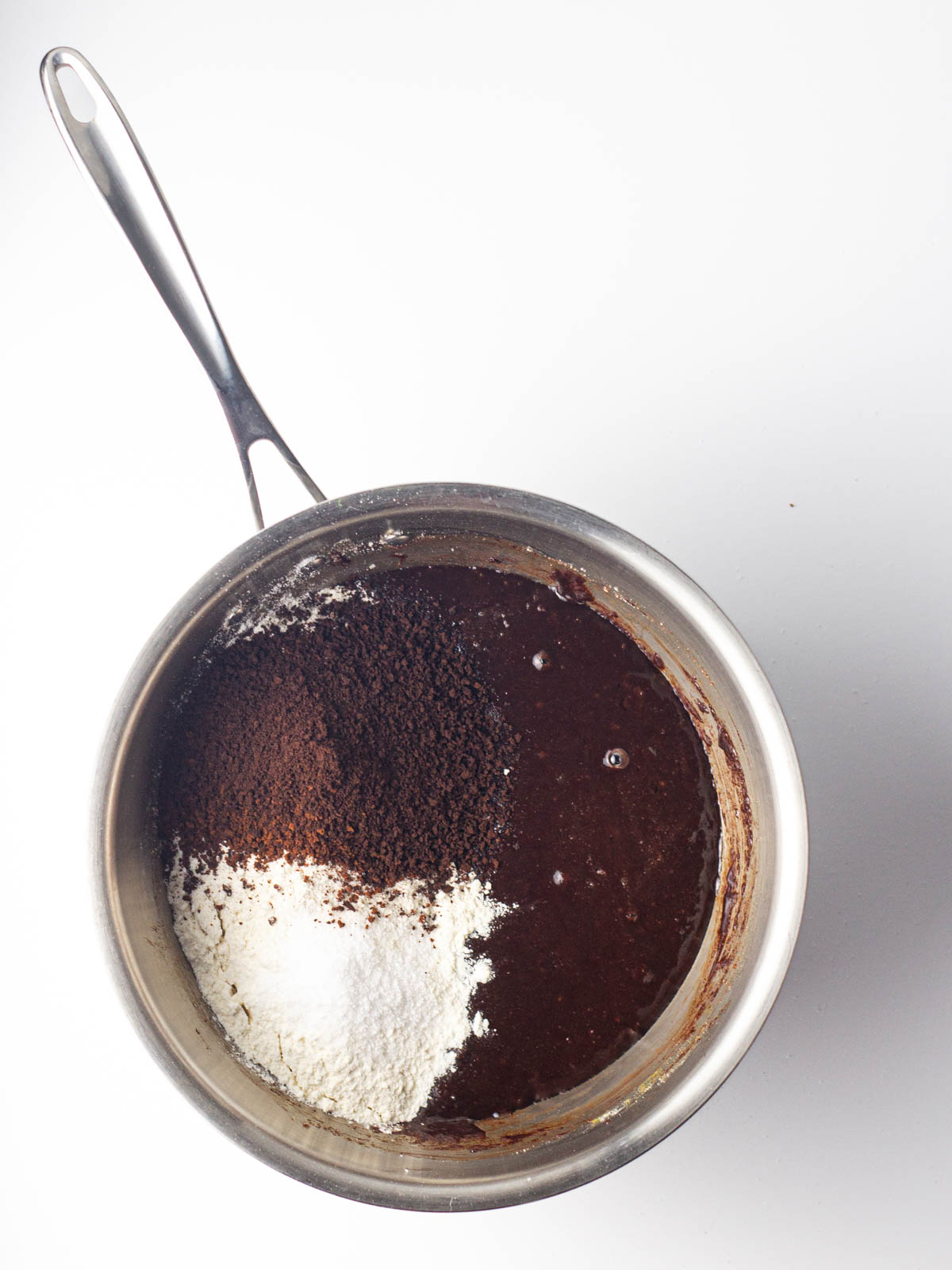 Flour, espresso powder, and salt added to the peppermint mocha brownie batter in a saucepan.