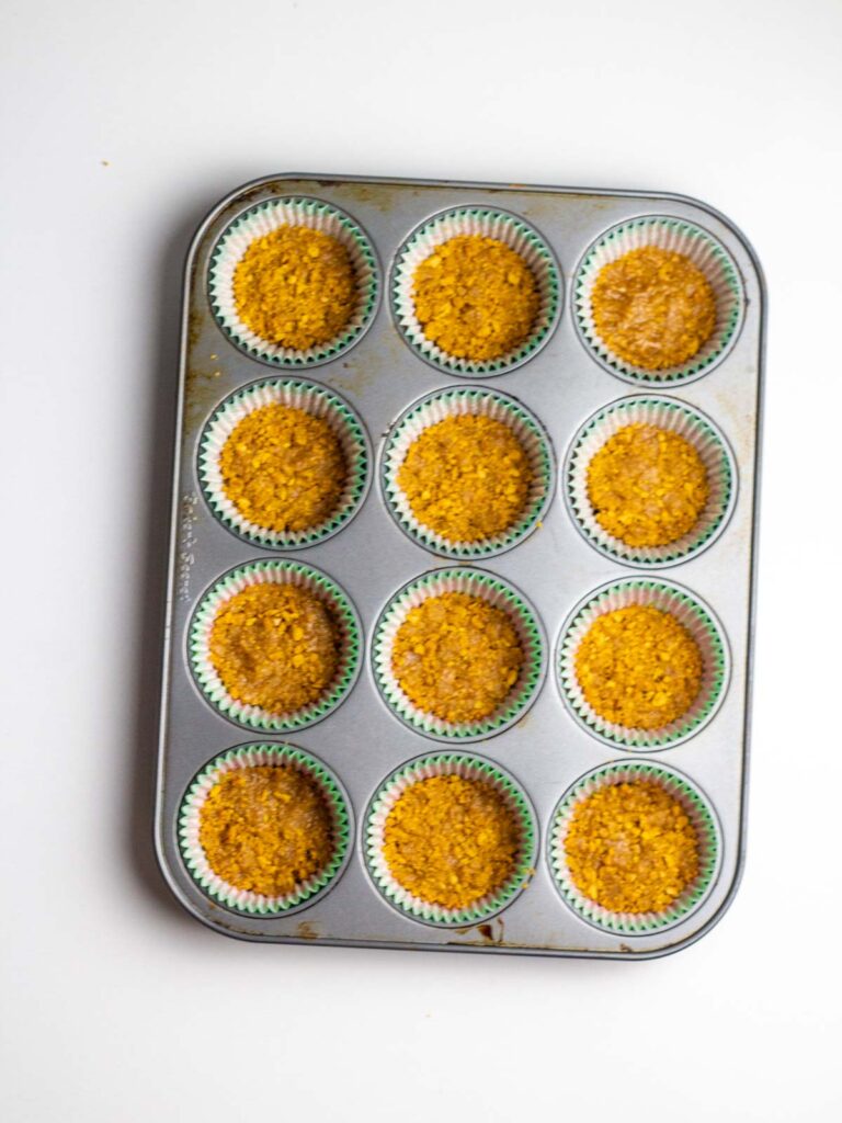 The lined muffin tin with gingersnap crumb crusts pressed into the liners.