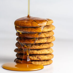 A stack of french toast cookies with maple syrup drizzling on to the stack.