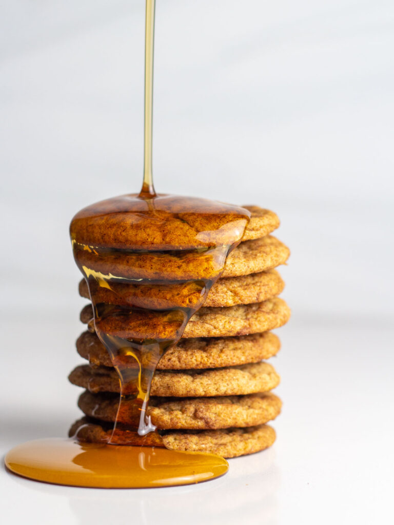 A stack of french toast cookies with maple syrup drizzling on to the stack.