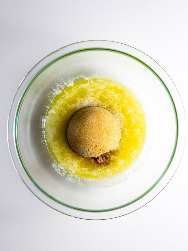 A clear glass bowl with melted butter and a heap of brown sugar.