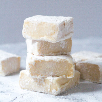 Side view of a stack of four Bailey's Marshmallows with a couple Bailey's Marshmallows scattered around the bottom of the stack