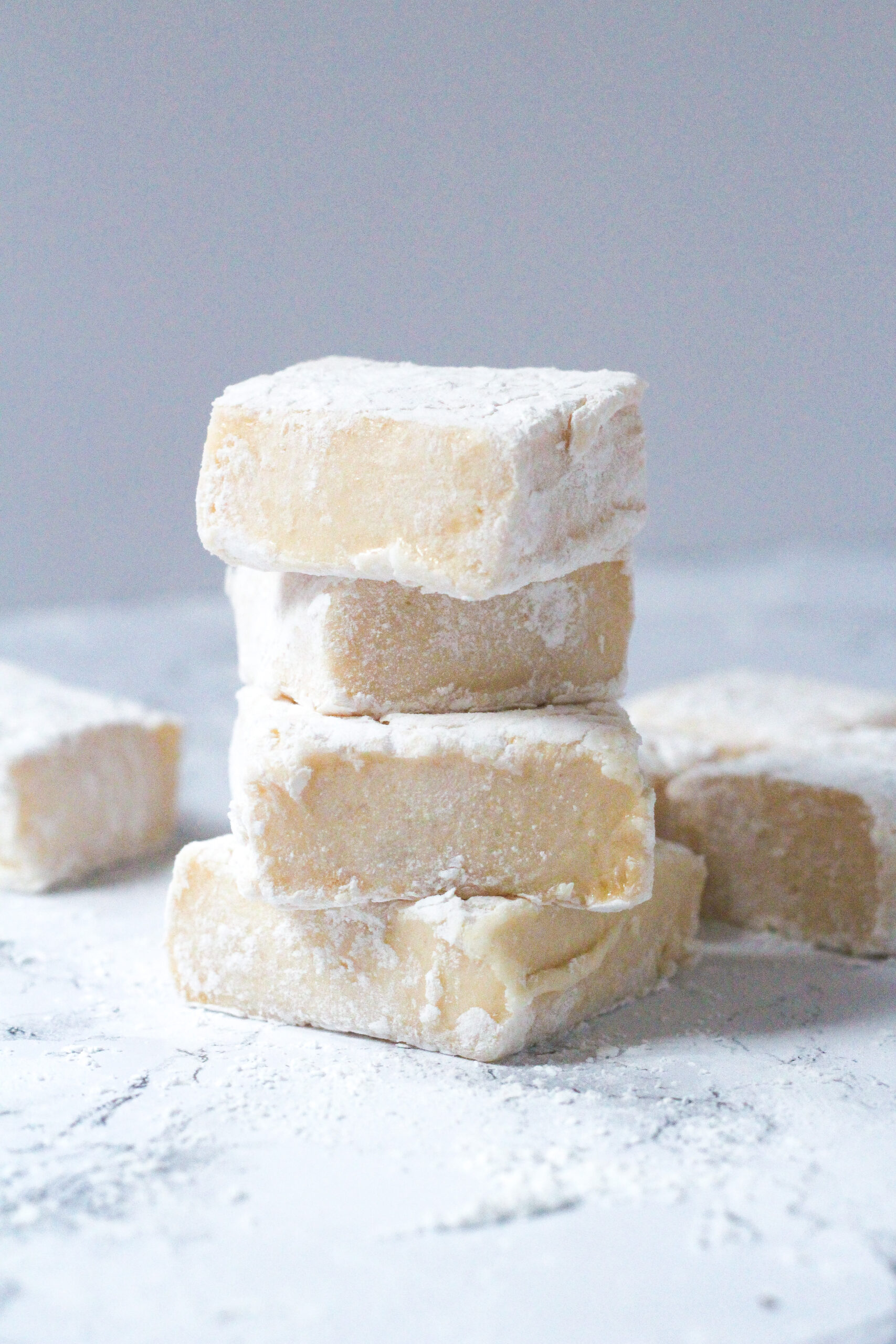 Side view of a stack of four Bailey's Marshmallows with a couple Bailey's Marshmallows scattered around the bottom of the stack